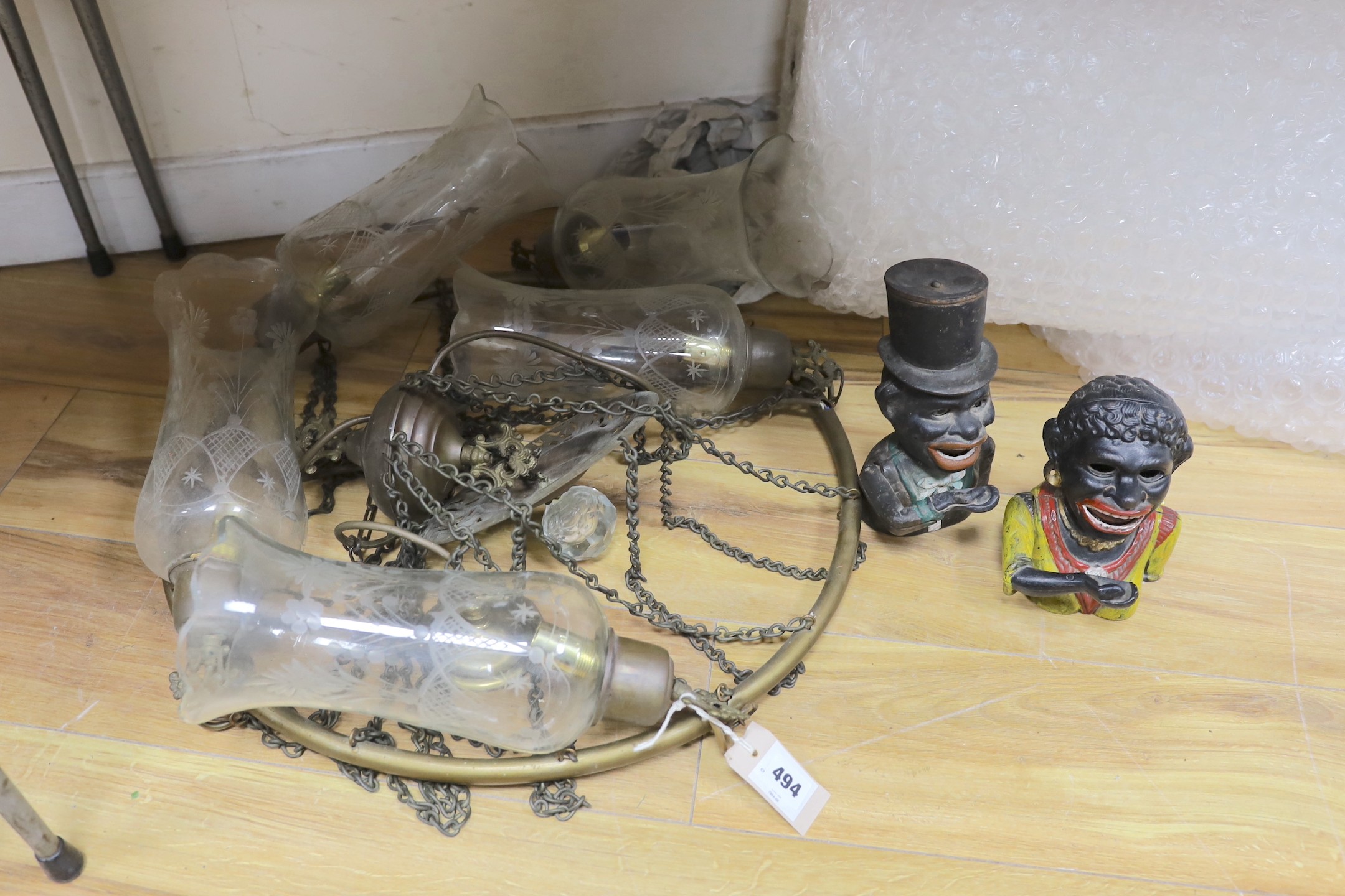A brass five-light chandelier with etched glass pendant shades, together with two figural cast iron money banks